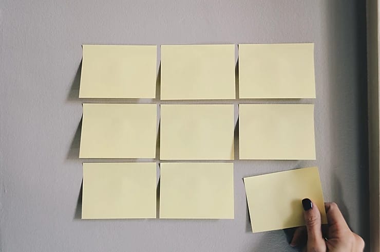 Woman hand getting one of the grouped yellow sticky notes in the wall